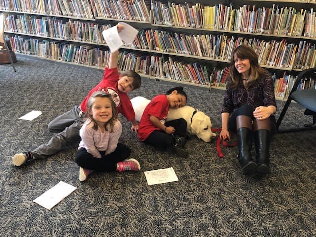 Children in a library with a Labrador Retriever - therapy dog